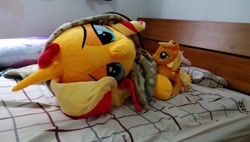 Size: 1200x683 | Tagged: safe, artist:nekokevin, character:applejack, character:fluttershy, character:sunset shimmer, species:earth pony, species:pegasus, species:pony, species:unicorn, bed, bedroom eyes, bedsheets, female, irl, life size, looking at you, lying down, mare, on side, photo, pillow, plushie, size difference, smiling, upside down