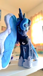 Size: 577x1024 | Tagged: safe, artist:nekokevin, character:princess luna, species:alicorn, species:pony, :3, female, hoof shoes, irl, looking at you, mare, peytral, photo, plushie, regalia, smiling, solo, table