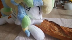 Size: 1207x679 | Tagged: safe, artist:ketika, character:vapor trail, species:pegasus, species:pony, g4, baguette, bread, cute, eating, eyes closed, food, happy, irl, kitchen, lying down, photo, plushie, solo, table, vaporbetes