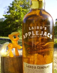 Size: 476x610 | Tagged: safe, artist:texasuberalles, character:applejack, species:earth pony, species:pony, alcohol, applejack (drink), bottle, brushable, female, freckles, hatless, irl, laird & company, laird's applejack, looking up, mare, missing accessory, namesake, photo, pun, raised hoof, raised leg, smiling, solo, toy