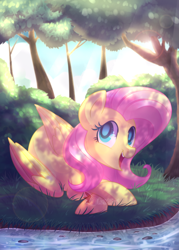 Size: 900x1260 | Tagged: safe, artist:drawntildawn, character:fluttershy, species:pegasus, species:pony, bush, cute, dappled sunlight, female, forest, looking at you, open mouth, prone, river, shade, shyabetes, smiling, solo, watermark