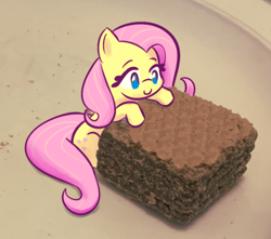 Size: 706x624 | Tagged: safe, artist:burgeroise, character:fluttershy, species:pony, chocolate, cute, female, food, irl, mare, no pupils, photo, ponies in food, ponies in real life, quadratini, shyabetes, sitting, size difference, smiling, solo, three quarter view, tiny, tiny ponies, wafer