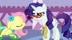 Size: 930x522 | Tagged: safe, screencap, character:fluttershy, character:rarity, episode:suited for success, g4, my little pony: friendship is magic, clothing, dress, duo, floppy ears, glasses, measuring tape, rarity's glasses, scrunchy face, sweat, wavy mouth