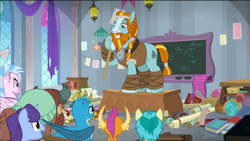 Size: 1574x888 | Tagged: safe, screencap, character:gallus, character:rockhoof, character:sandbar, character:silverstream, character:smolder, character:yona, species:earth pony, species:pony, episode:a rockhoof and a hard place, g4, my little pony: friendship is magic, beard, braid, classroom, desk, facial hair, male, moustache, rockhoof's shovel, shovel, stallion