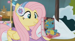 Size: 1352x754 | Tagged: safe, screencap, character:fluttershy, species:pegasus, species:pony, episode:best gift ever, g4, my little pony: friendship is magic, clothing, cute, earmuffs, female, happy, holly the hearths warmer doll, mare, shyabetes, smiling, solo, sweater, winter