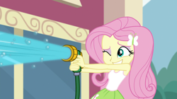 Size: 1912x1072 | Tagged: safe, screencap, character:fluttershy, equestria girls:dance magic, g4, my little pony:equestria girls, bubble, canterlot high, car wash, clothing, cute, eyeshadow, female, grin, hose, makeup, one eye closed, shyabetes, skirt, sleeveless, smiling, solo, tank top, this will end in wet tshirts, water, wink
