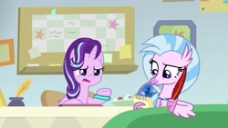 Size: 1920x1080 | Tagged: safe, screencap, character:silverstream, character:starlight glimmer, species:classical hippogriff, species:hippogriff, species:pony, species:unicorn, episode:student counsel, beak, bracelet, claws, desk, duo, female, frown, guidance counselor, inkwell, jewelry, looking down, mare, notepad, open mouth, quill, raised eyebrow, raised hoof, starlight's office, talking, talons, teacher and student, teenager