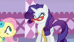 Size: 880x496 | Tagged: safe, screencap, character:fluttershy, character:rarity, episode:suited for success, g4, my little pony: friendship is magic, duo, eyes closed, glasses, measuring tape, messy mane, rarity's glasses, scrunchy face, sweat