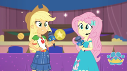 Size: 1057x594 | Tagged: safe, screencap, character:applejack, character:fluttershy, episode:best in show: the victory lap, g4, my little pony:equestria girls, looking at you, microphone, smiling