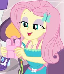 Size: 857x985 | Tagged: safe, screencap, character:fluttershy, character:rarity, equestria girls:holidays unwrapped, g4, my little pony:equestria girls, bunny ears, camera, canterlot mall, chair, clothing, cropped, cute, dashing through the mall, dress, female, flower, geode of fauna, gift giving, hairclip, happy, jewelry, lidded eyes, looking down, magical geodes, mall, necklace, present, shyabetes, sitting, smiling, table, waistband