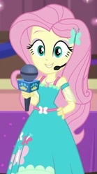 Size: 329x590 | Tagged: safe, screencap, character:fluttershy, episode:best in show: the victory lap, g4, my little pony:equestria girls, clothing, cropped, cute, dress, geode of fauna, hand on hip, looking at you, magical geodes, microphone, shyabetes, smiling, smiling at you, solo