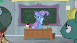 Size: 1920x1080 | Tagged: safe, screencap, character:trixie, character:yona, species:pony, species:unicorn, species:yak, episode:a horse shoe-in, g4, my little pony: friendship is magic, apple, cape, clothing, desk, female, food, hat, lidded eyes, mare, solo focus, trixie's cape, trixie's hat
