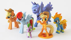 Size: 630x354 | Tagged: artist needed, source needed, safe, character:applejack, character:princess luna, character:rainbow dash, character:spike, character:spitfire, species:alicorn, species:dragon, species:earth pony, species:pegasus, species:pony, 3d print, clothing, cowboy hat, female, figure, hat, irl, male, mare, model, my little pony, photo, rearing, s1 luna, toy, uniform, wonderbolts uniform
