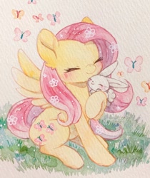 Size: 1007x1200 | Tagged: safe, artist:kemaaari, character:angel bunny, character:fluttershy, species:pegasus, species:pony, species:rabbit, g4, blushing, butterfly, cute, ear fluff, eyes closed, female, flower, flower in hair, grass, hug, mare, painting, shyabetes, simple background, sitting, solo, traditional art, watercolor painting, wings